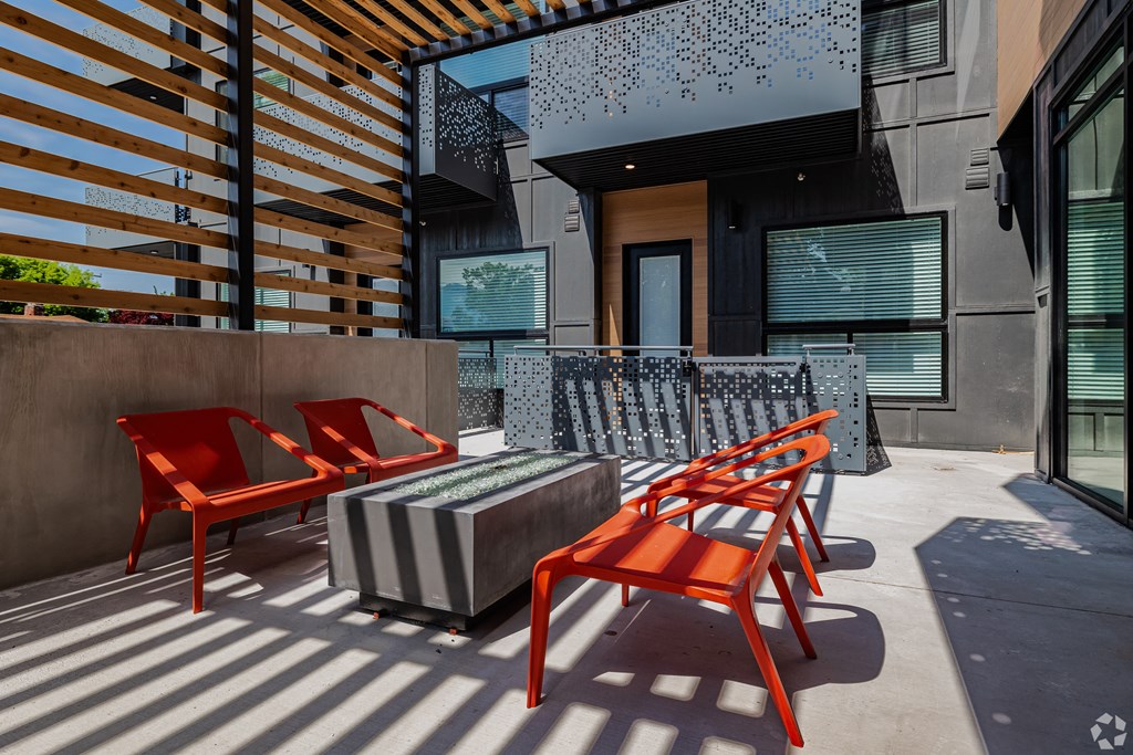 a patio with red chairs and a and a firepit at Lotus Gallacher luxury apartments for rent in Salt Lake City, UT