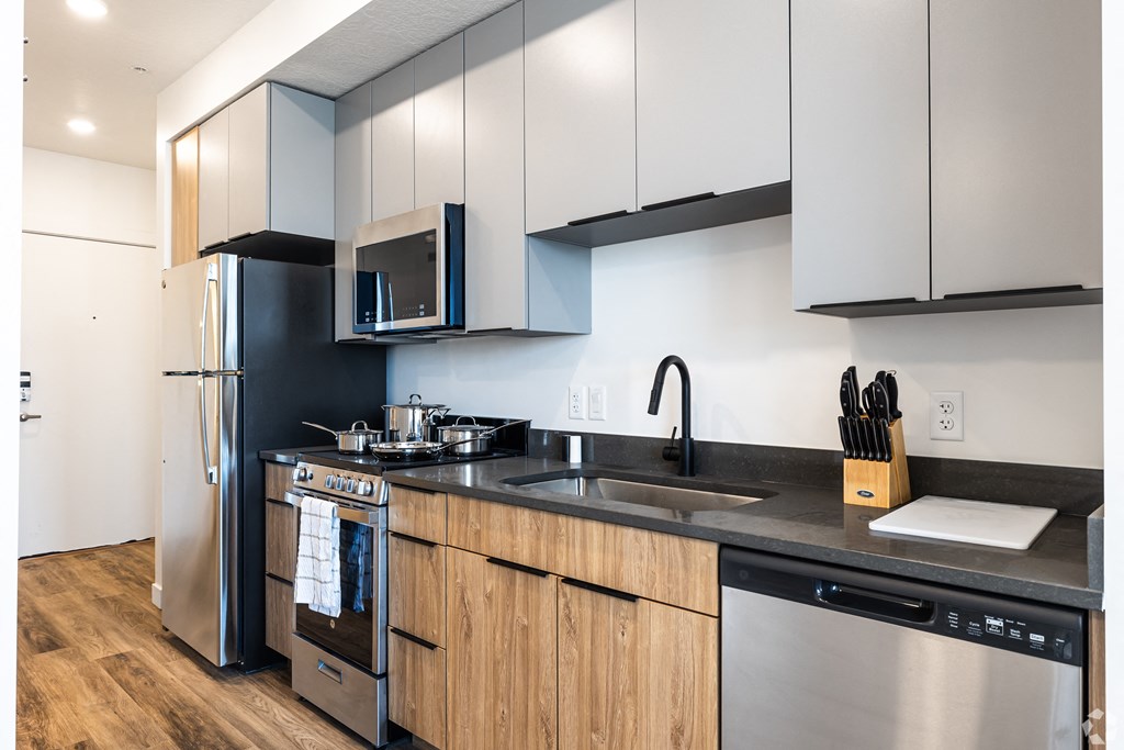 a kitchen with stainless steel appliances and black counter tops at Lotus Gallacher luxury apartments for rent in Salt Lake City, UT