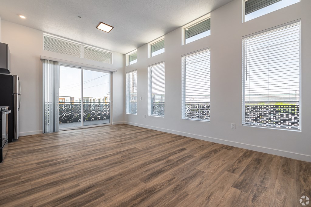 an empty living room with wood flooring and windows at Lotus Gallacher luxury apartments for rent in Salt Lake City, UT