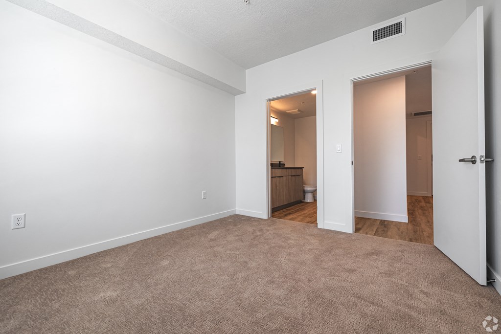 an empty living room with white walls and a door to a bathroom at Lotus Gallacher luxury apartments for rent in Salt Lake City, UT