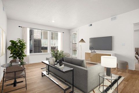 A modern living room with a grey couch and a glass coffee table.