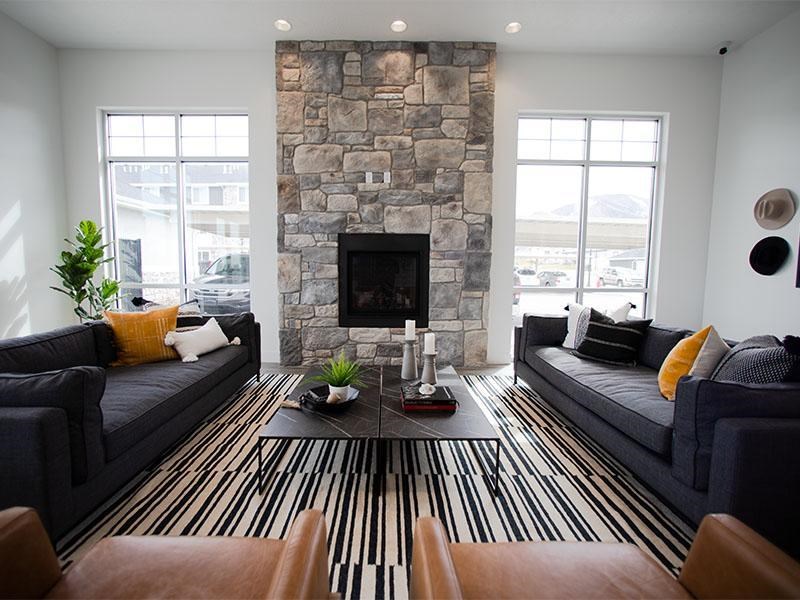 A living room with a stone fireplace and striped rug.
