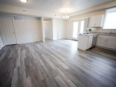 A spacious room with wood flooring and white walls.