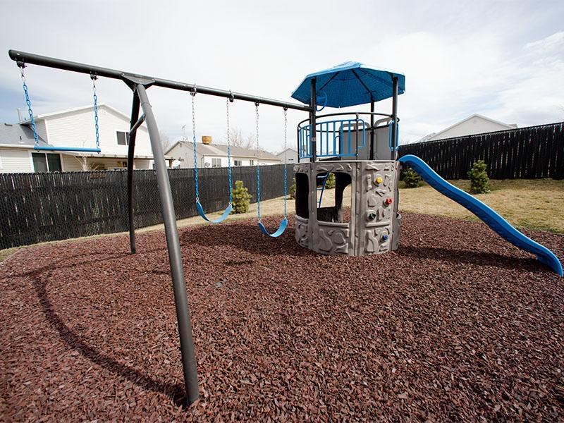 A playground with a blue slide and a grey structure.