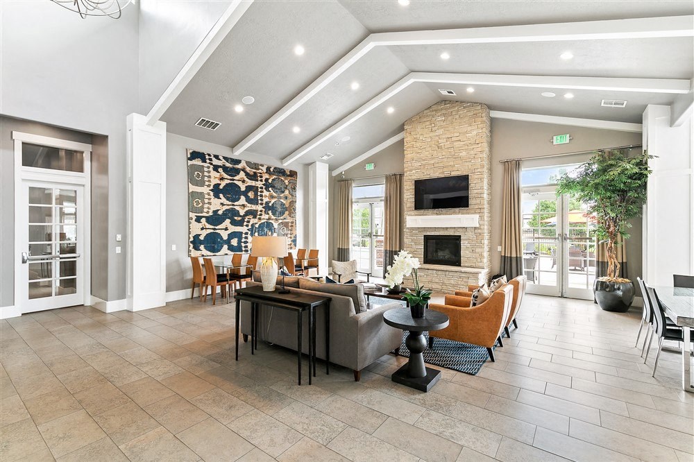 a large and modern fireplace area with vaulted ceilings and couches and chairs at Outlook Apartments for rent in Springville and Provo, UT.