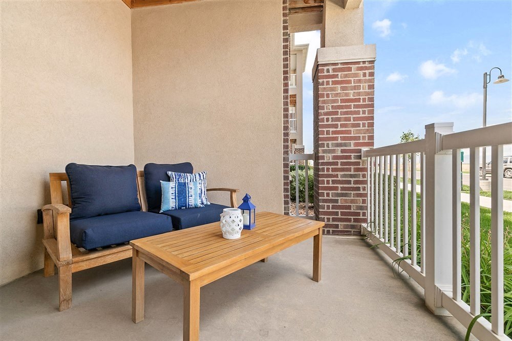 a patio with a couch and a table on a balcony from Outlook Apartments in Springville and Provo, Utah