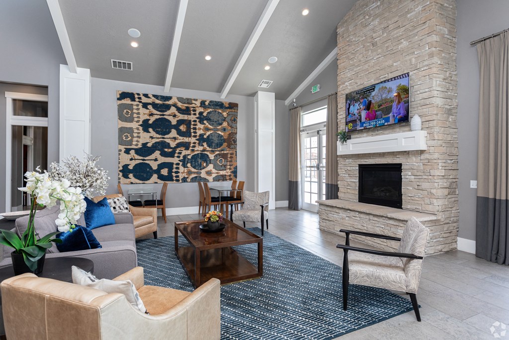 a large and modern fireplace area with couches and chairs and a tv at Outlook Apartments for rent in Springville and Provo, UT.