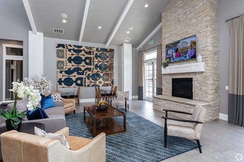 A living room with a stone fireplace and a large tapestry hanging on the wall.
