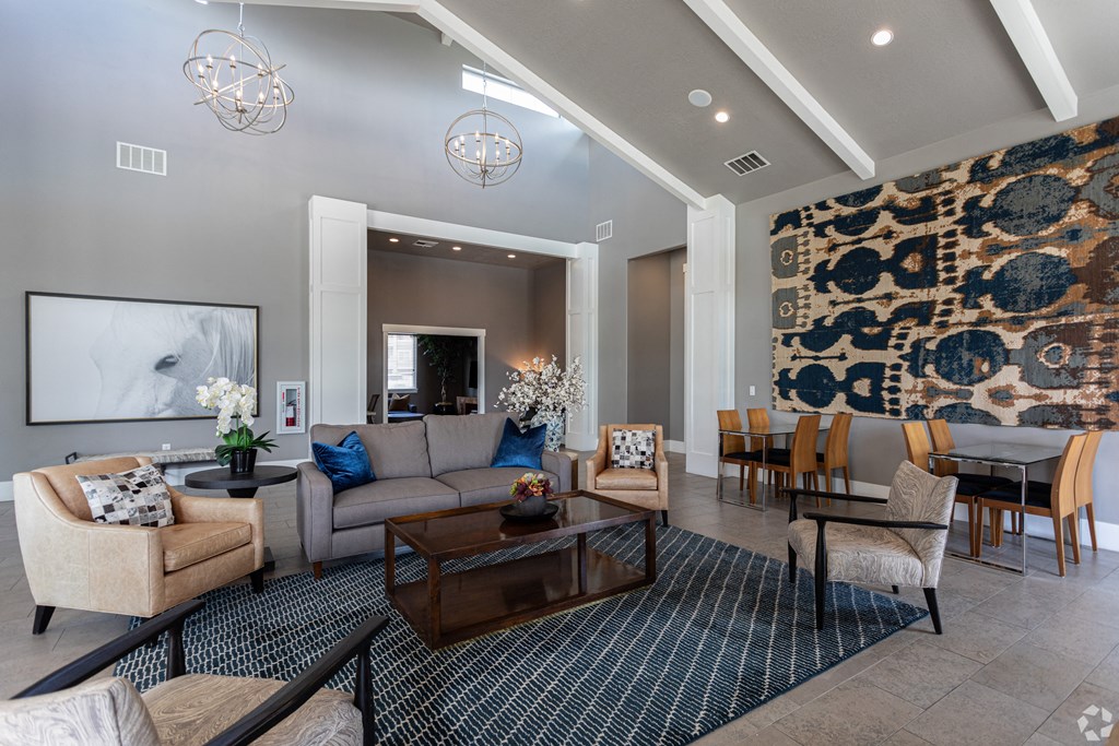 a large living room with couches, chairs, a table, and vaulted ceilings at Outlook Apartments for rent in Springville and Provo, UT.