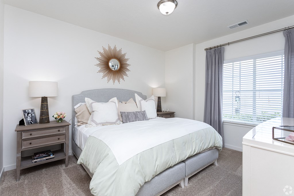 a bright and spacious bedroom with a large bed and a window at Outlook Apartments for rent in Springville and Provo, UT.