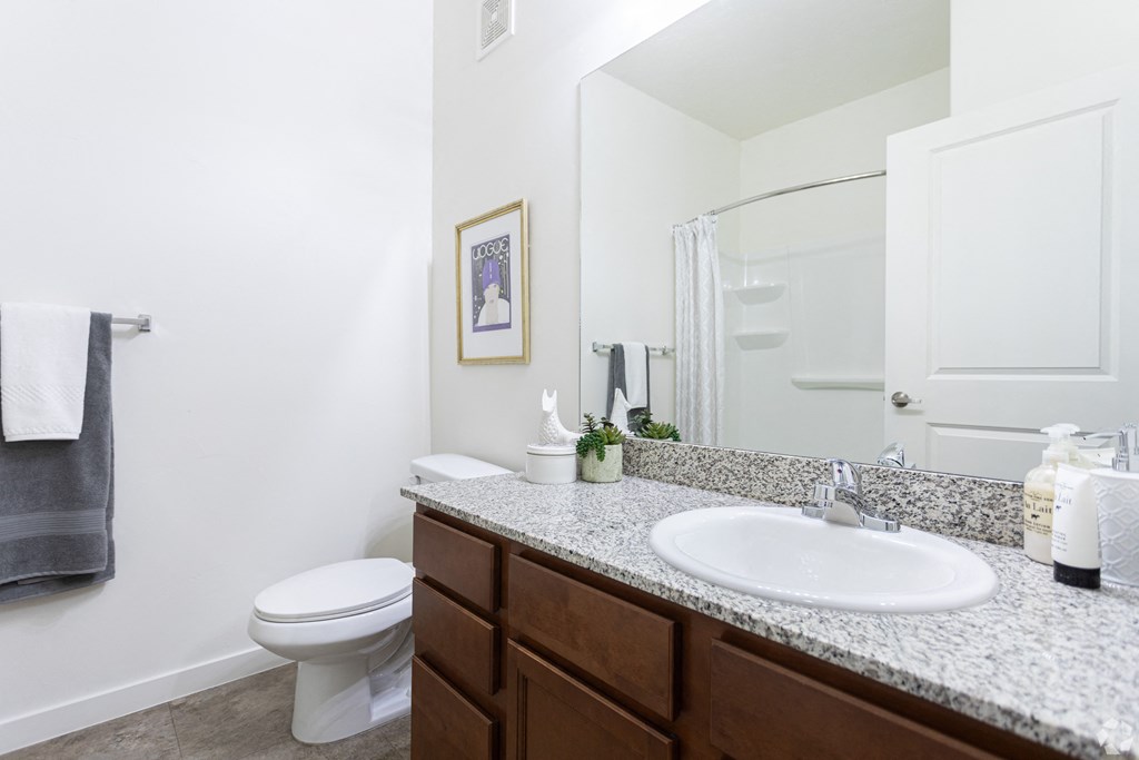 a bright bathroom with a sink, toilet and a mirror at Outlook Apartments for rent in Springville and Provo, UT.