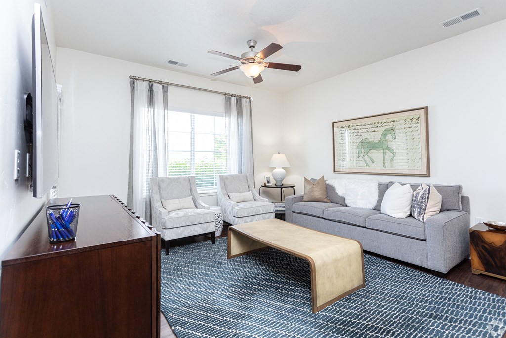 a modern living room with a couch and two chairs and a ceiling fan at Outlook Apartments for rent in Springville and Provo, UT.