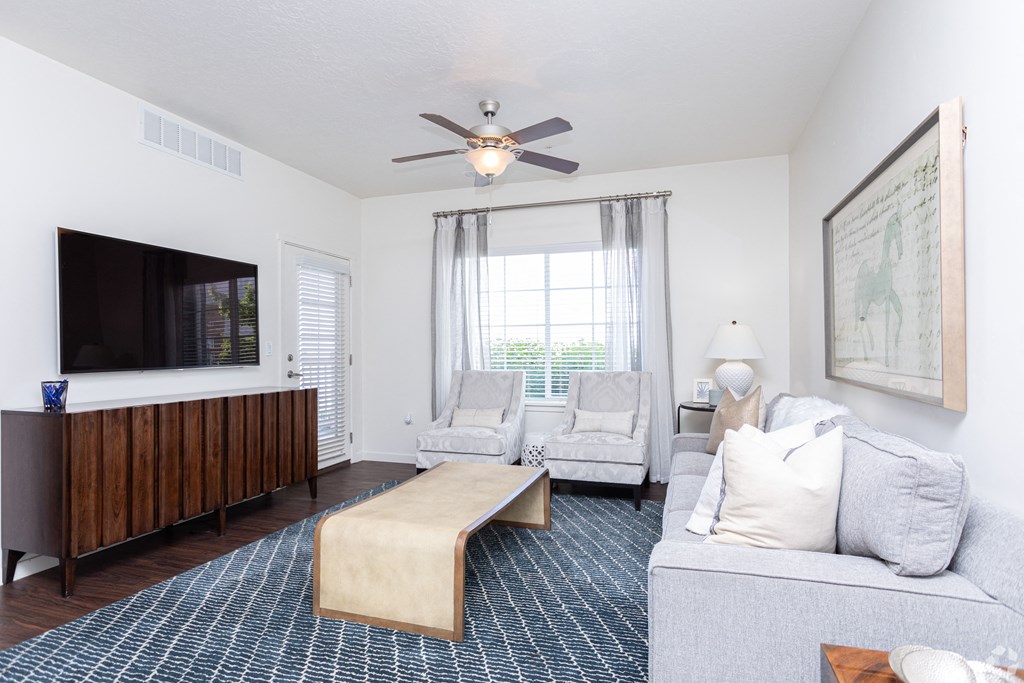 a bright living room with a ceiling fan and a tv at Outlook Apartments for rent in Springville and Provo, UT.