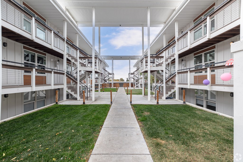 A long white corridor with a walkway in the middle of apartment buildings.