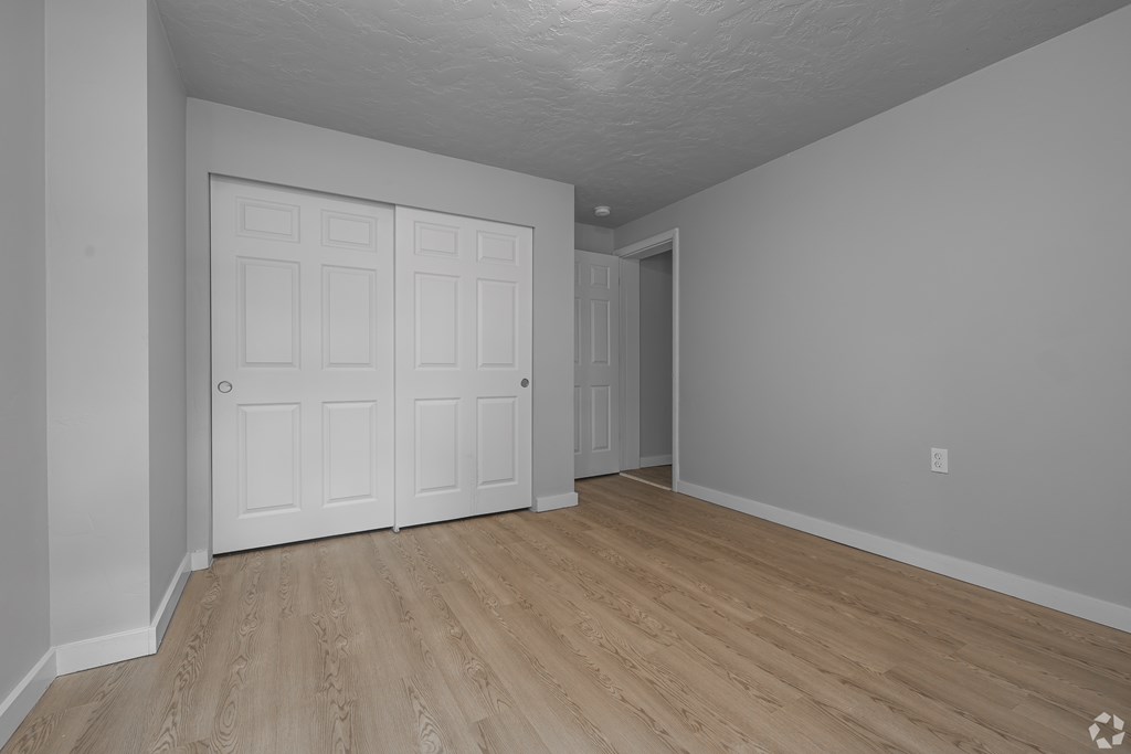 A room with a white door and wooden flooring.