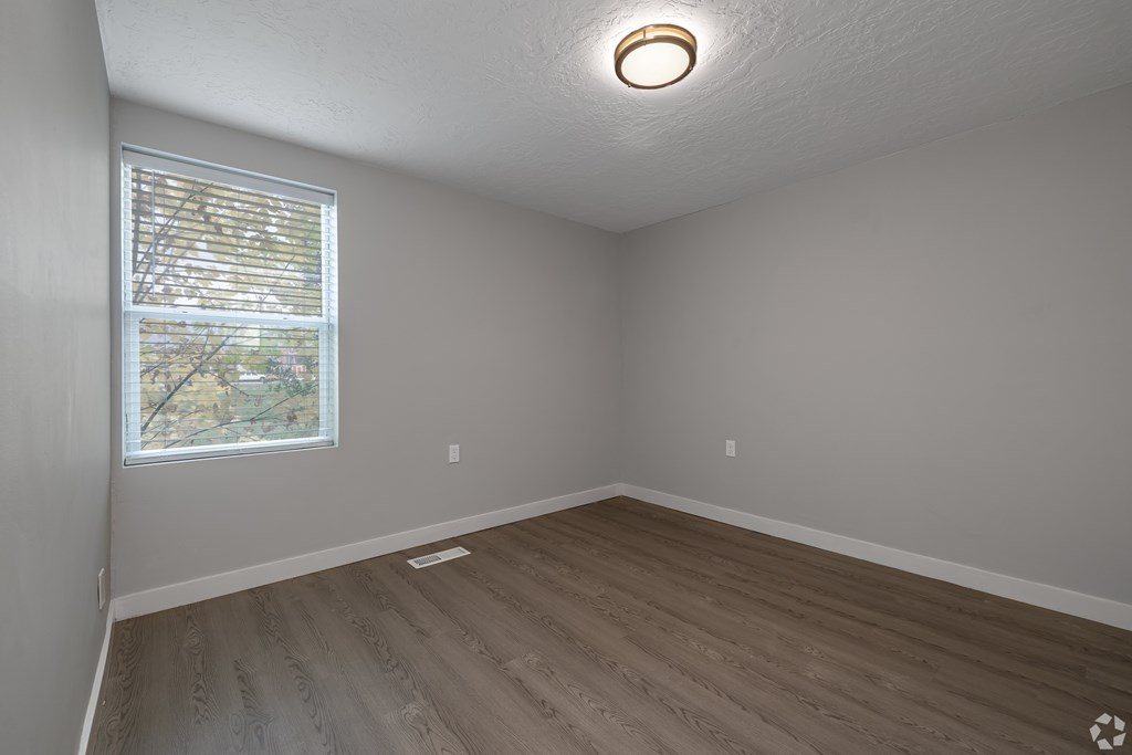 A room with a window and wooden flooring.