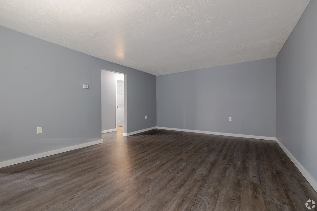 A room with wooden flooring and a doorway leading to another room.