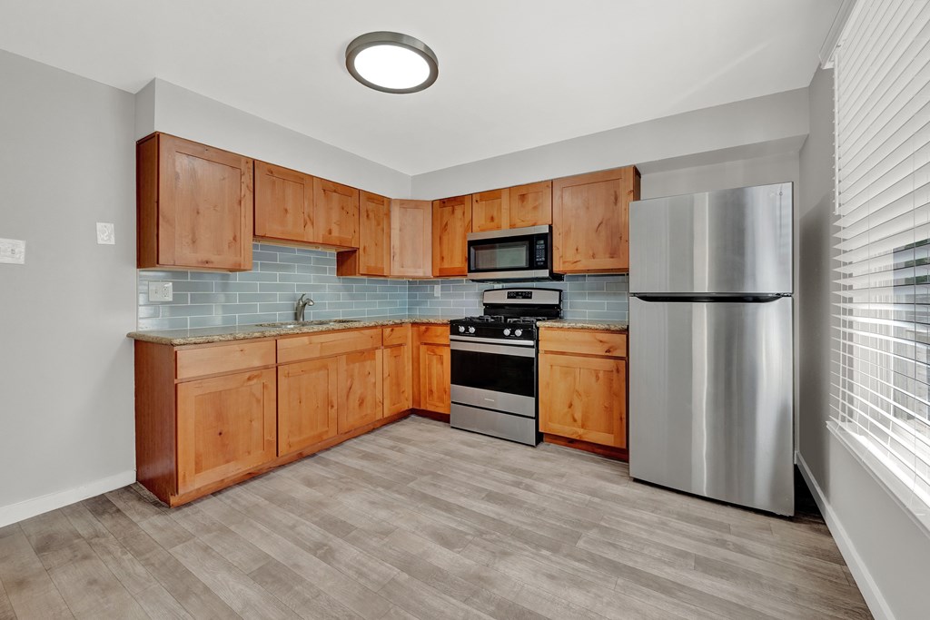 A kitchen with wooden cabinets and a stainless steel refrigerator.