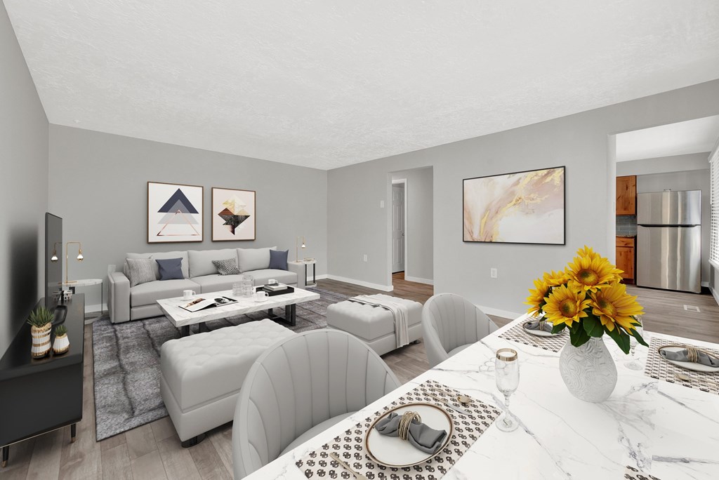 A modern living room with a grey sofa set and a white dining table set with a vase of sunflowers.