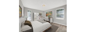 A bedroom with a bed, desk, and a painting on the wall.