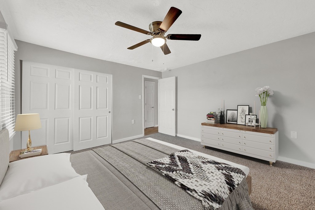 A bedroom with a bed, a dresser, and a ceiling fan.