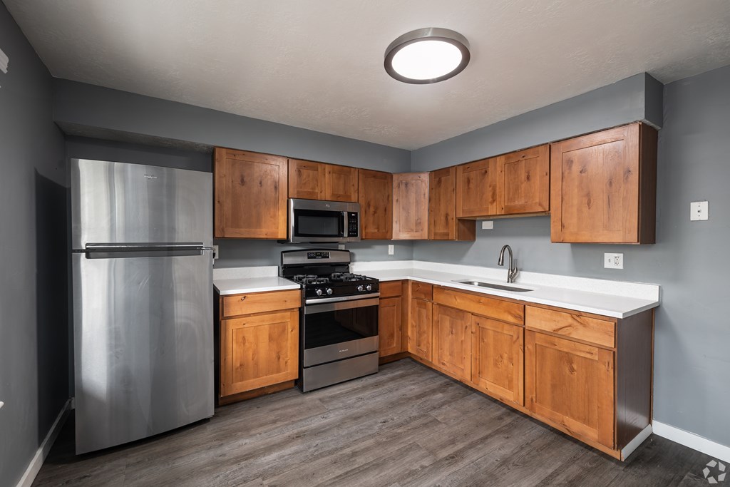A kitchen with wooden cabinets and a stainless steel refrigerator.