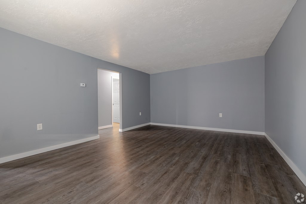 A room with wooden flooring and a door in the background.