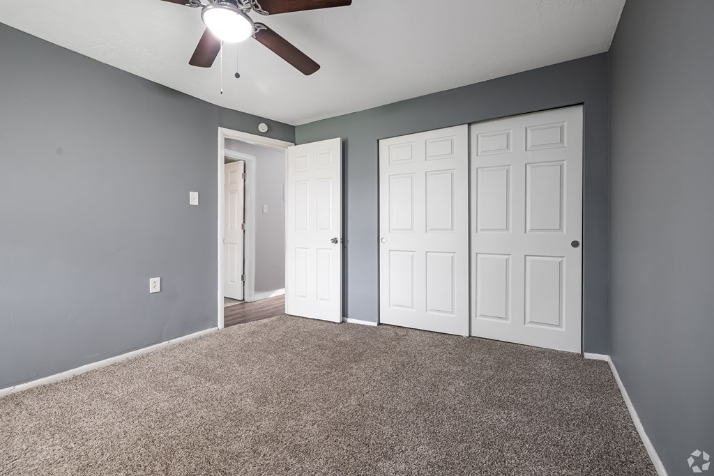 A room with a ceiling fan and two doors.