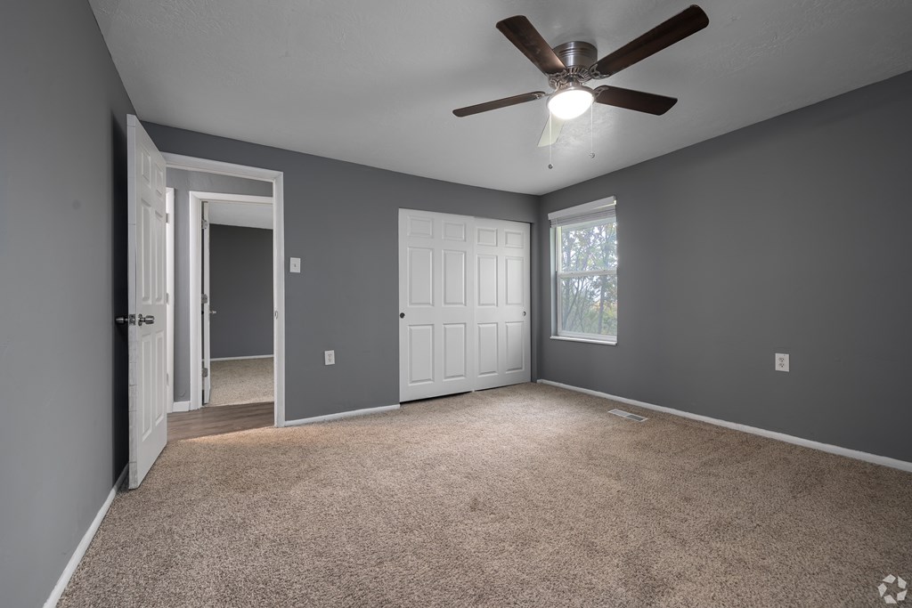 A room with a ceiling fan and carpeted floor.