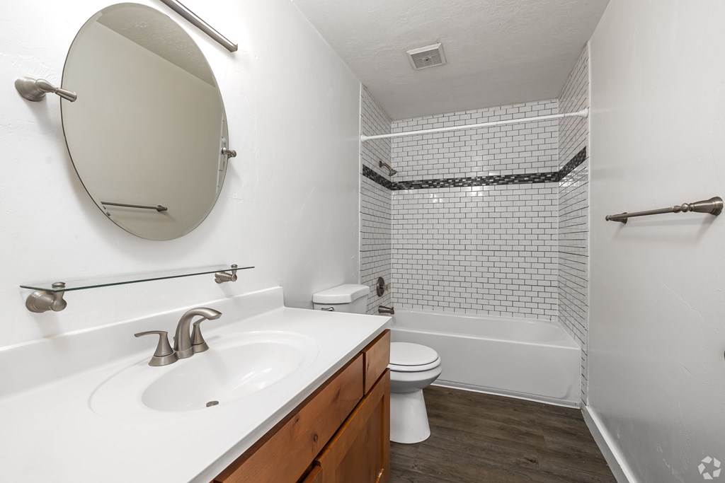 A white sink with a round mirror above it.