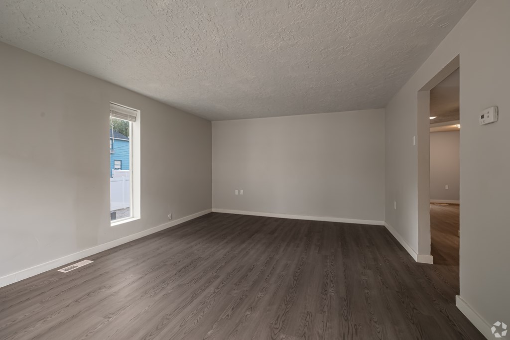 Empty room with wooden flooring and white walls.