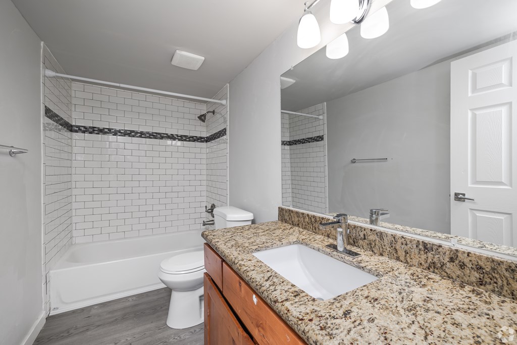 A bathroom with a granite countertop and a white toilet.