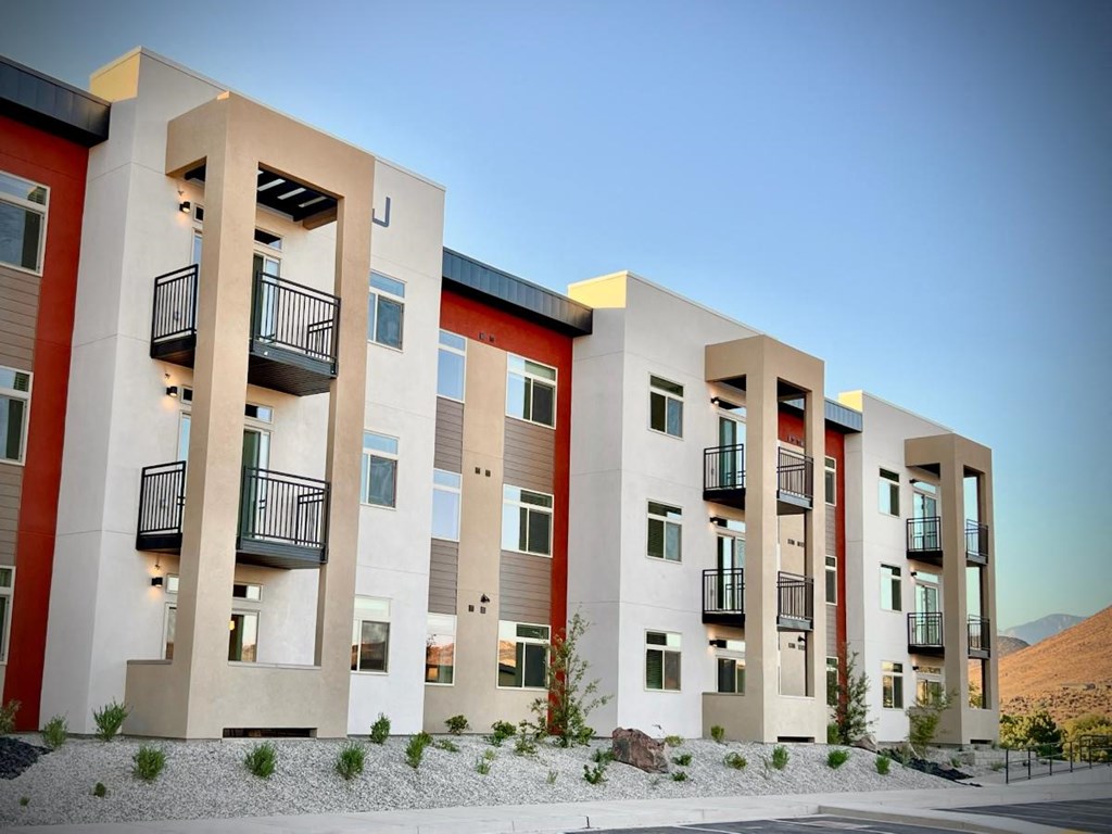 a row of modern apartments with balconies and a desert background