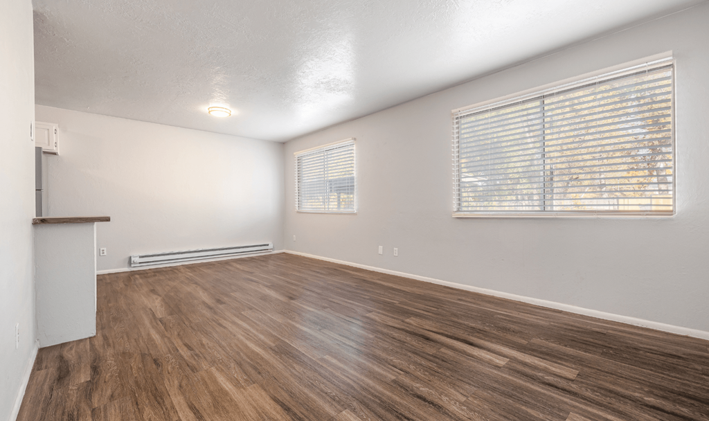 A room with wooden flooring and a window with blinds.