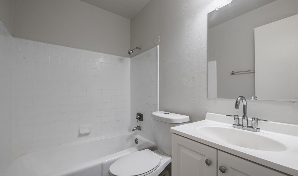 A white bathroom with a toilet, sink, and bathtub.