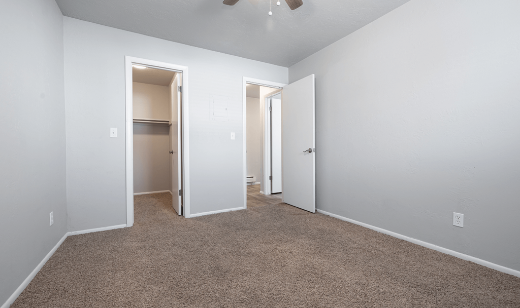 A room with carpeted floor and two open doors.