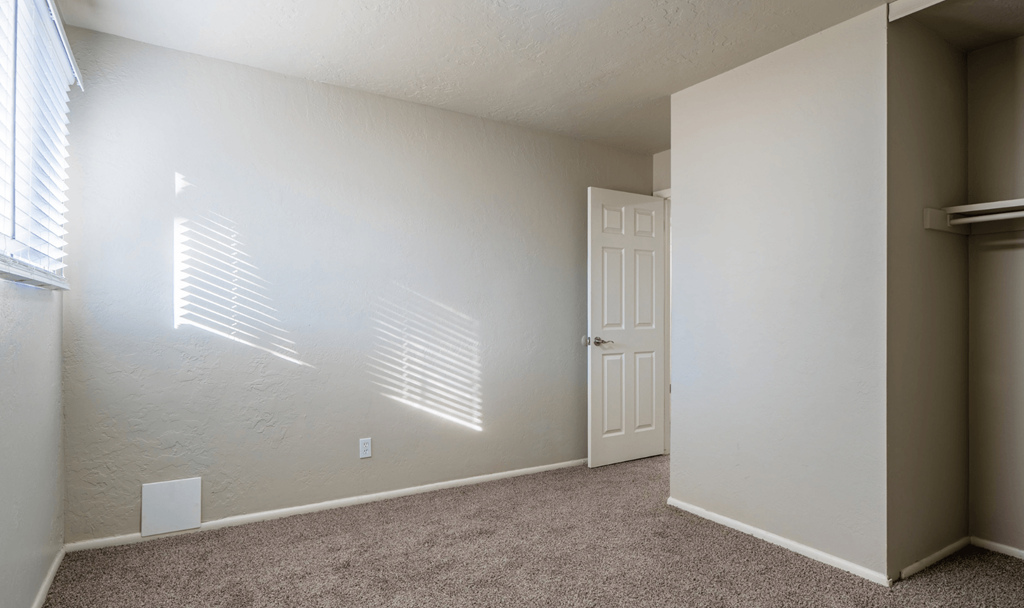 A room with a door and a window with blinds.
