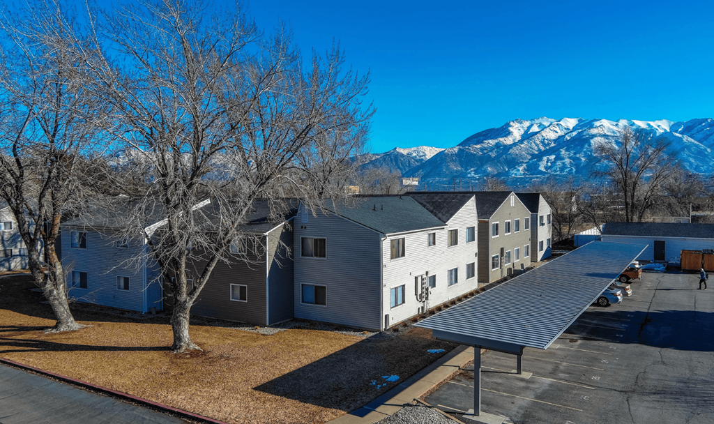 A large building with a grey roof is surrounded by bare trees.