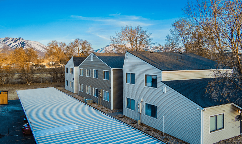 A modern house with a grey roof and a car parked in front.