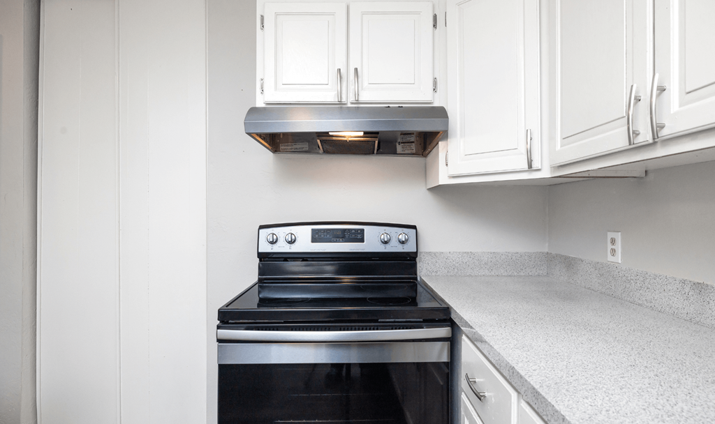 A black stove top oven with a silver range hood above it.