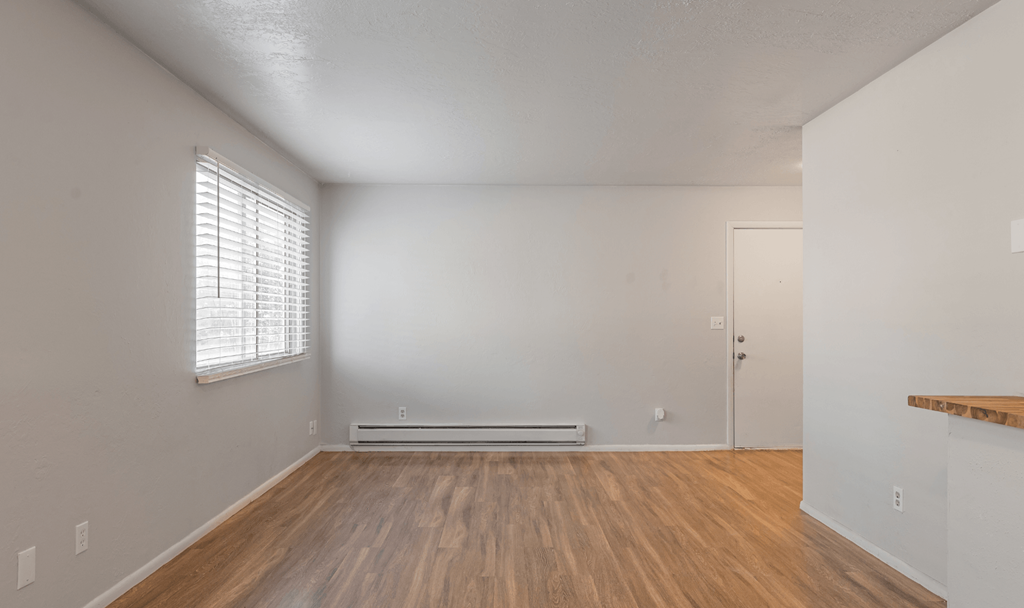A room with wooden floors and a window with blinds.