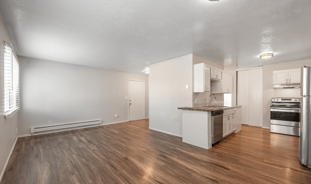 A spacious kitchen with white cabinets and a wooden floor.