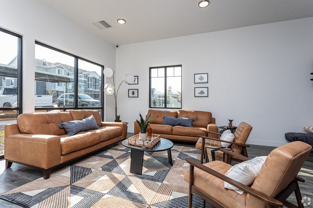 A living room with brown leather furniture and a patterned rug.
