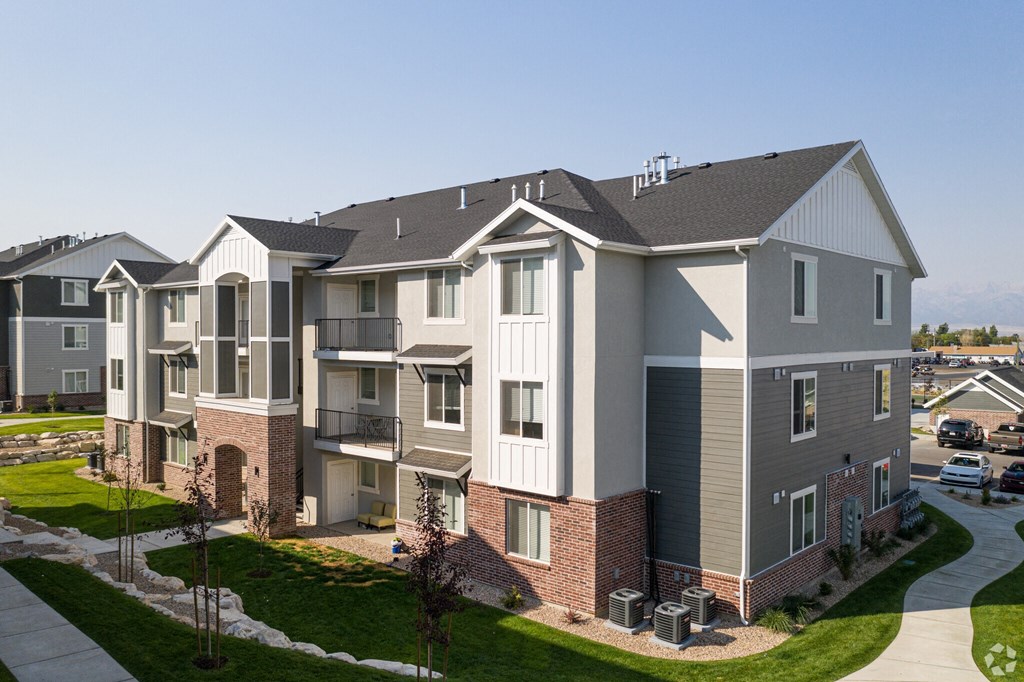 A large, modern apartment building with a well-maintained lawn in front.
