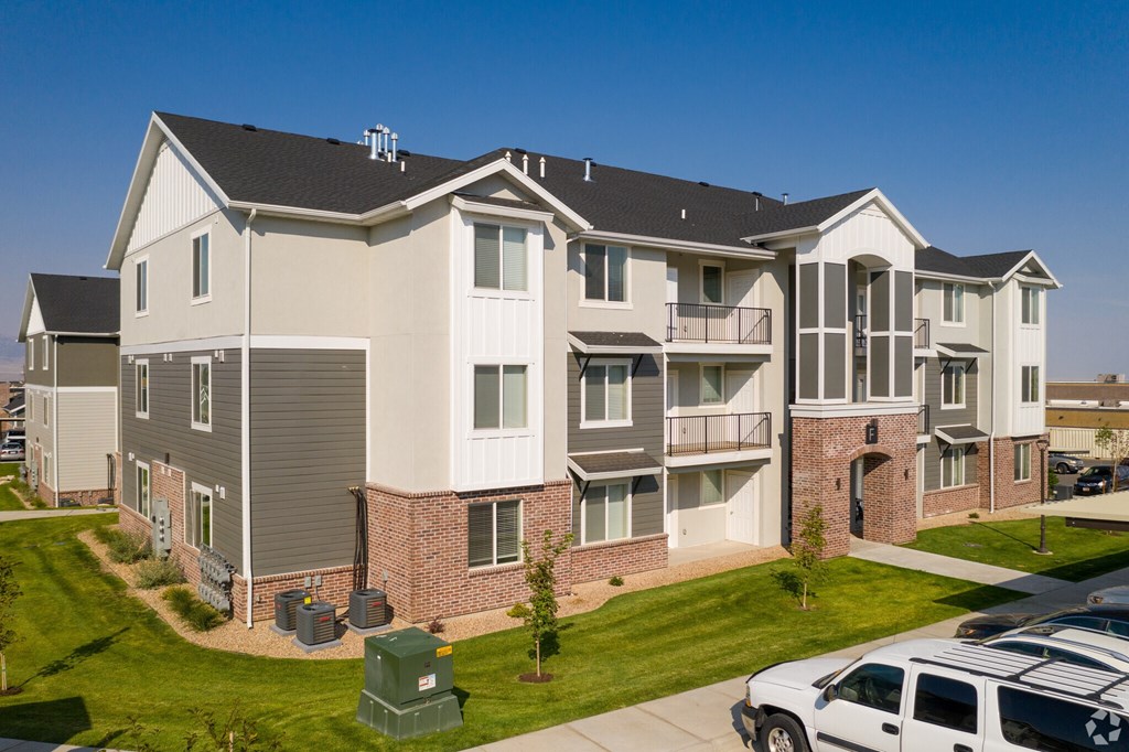 A white car is parked in front of a two-story apartment building.