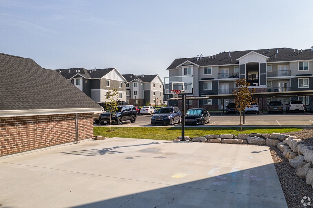 A parking lot in front of apartment buildings with cars parked.