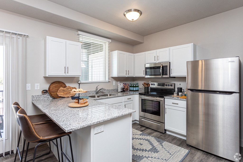 A kitchen with a refrigerator, oven, and sink.
