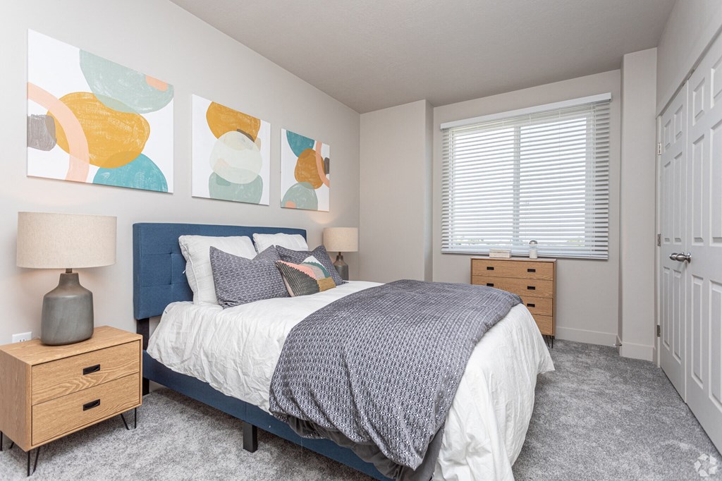 A bedroom with a bed, nightstand, and a painting on the wall.