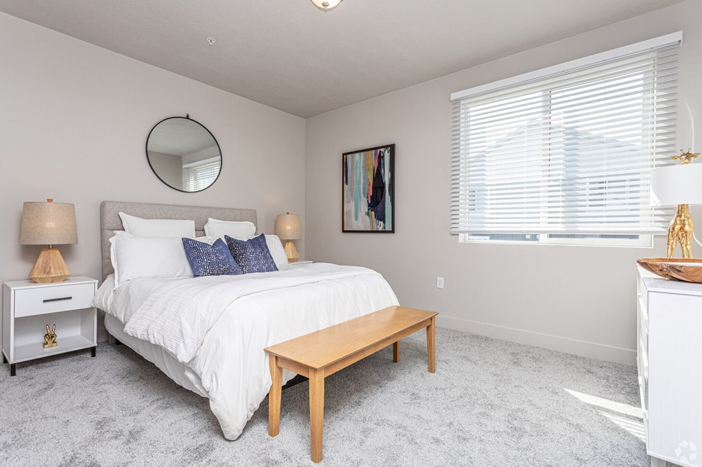 A bedroom with a large bed, a round mirror, and a painting on the wall.