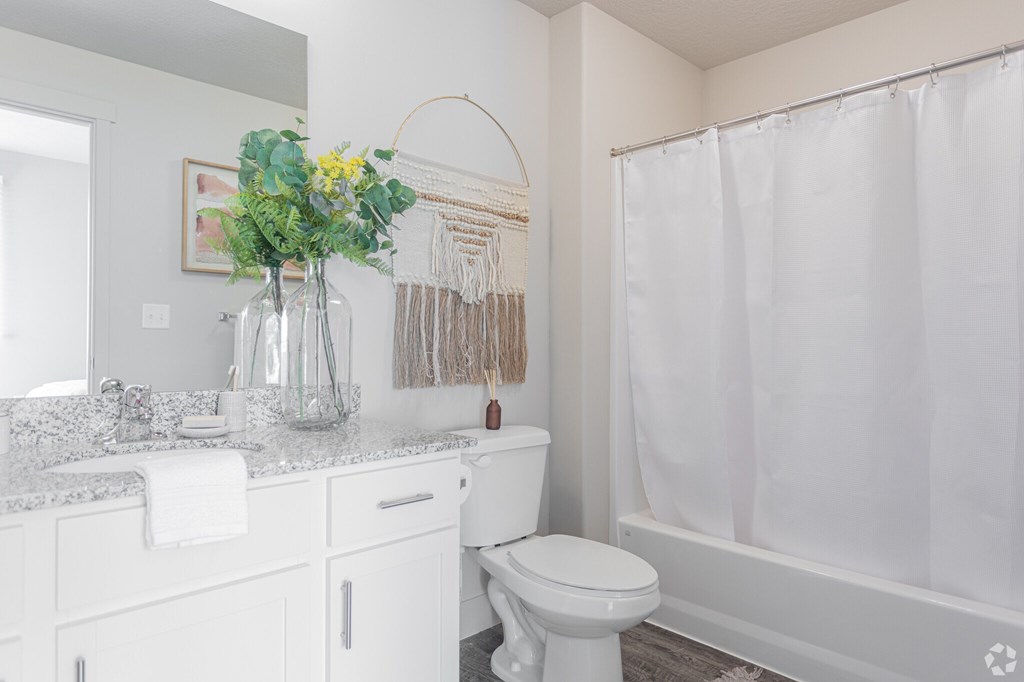 A white bathroom with a toilet, sink, and shower.